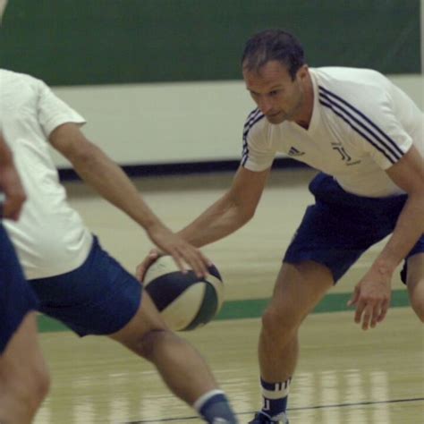 Two Men Playing Basketball On A Court With One Holding The Ball In His