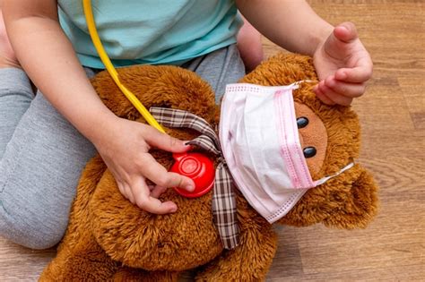 Premium Photo Little Girl Healing A Teddy Bear In A Medical Mask