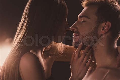 Tender Naked Couple Kissing And Looking At Each Other On Brown With Backlit Stock Image