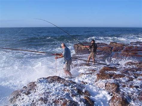 Two Men Are Fishing On The Rocky Shore