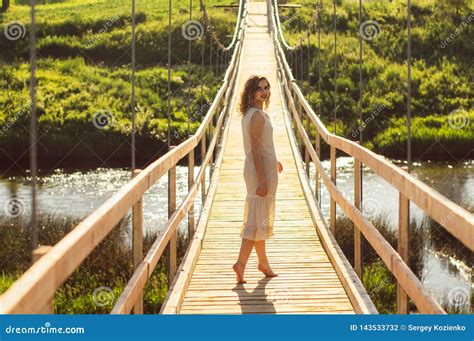 Girl Standing On The Center Of The Wooden Bridge Across The River Stock