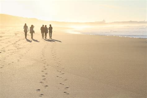 Premium Photo | Group of people walking in beach in sunset