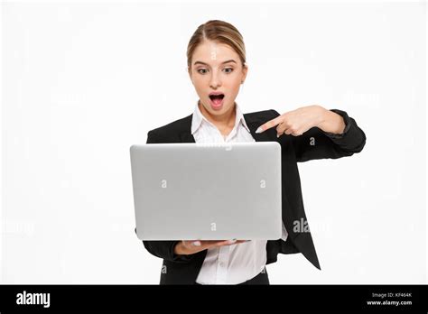 Shocked Blonde Business Woman Holding Laptop Computer And Pointing At Him Over White Background