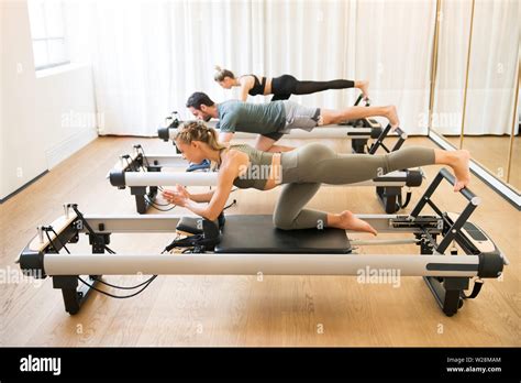 Group Of Friends Doing Pilates Kneeling Glutes Exercises On Reformer