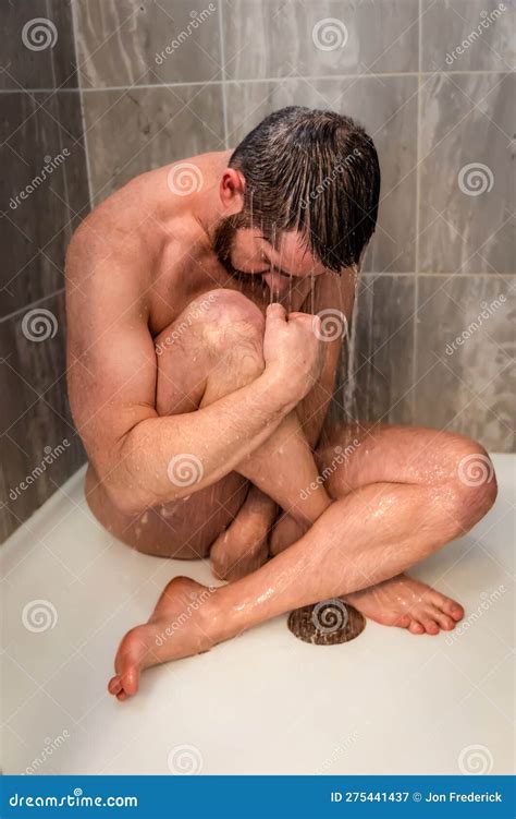 Nude Male Model Sitting In Floor Of Shower Trying To Cover Himself As