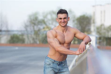 Sports Man With Naked Torso Holds His Hand Behind His Head And Muscles