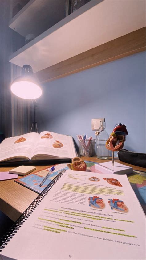 An Open Book Sitting On Top Of A Desk Next To A Lamp And Some Papers