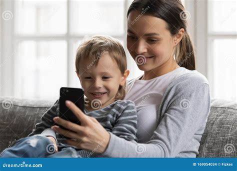 La Jeune Maman Et Peu De Fils Observent La Vidéo Sur La Cellule