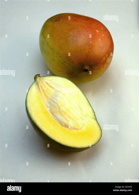 Whole Mango And Mango Sliced In Half Against White Background Stock