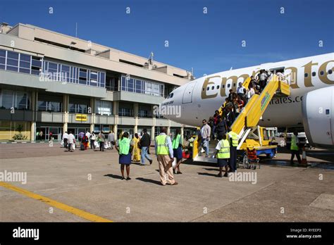 Passengers disembarking an Emirates airline flight walk toward the arrivals lounge at Entebbe ...