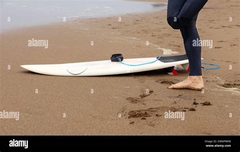 Cut Out Of A Surfers Legs On The Beach With A Surfboard Stock Photo