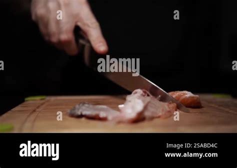 Close Up Of Hands Slicing Fresh Salmon Fillet On A Dark Background