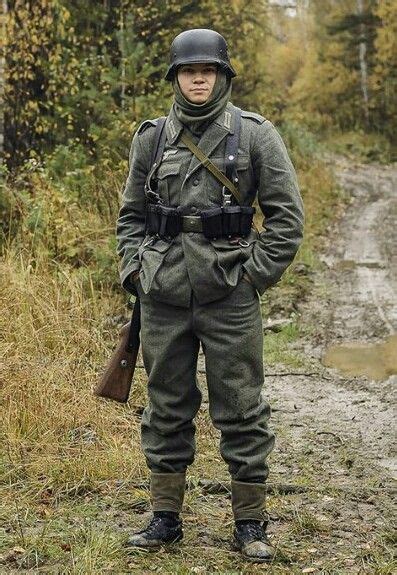 A Man In An Army Uniform Standing On A Dirt Road