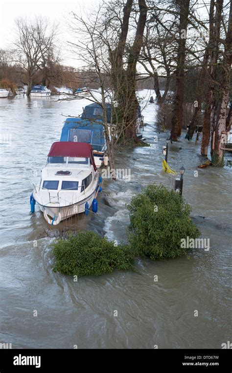 A row of boats on flood water on the River Thames, water has flooded ...