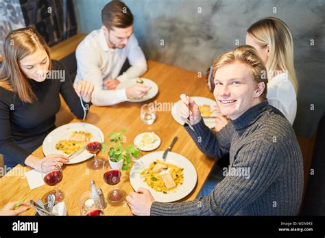 Group of young people having lunch or dinner in restaurant or bistro Stock Photo - Alamy