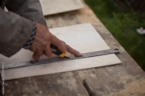 Senior Elderly Carpenter Using A Straightedge To Draw A Line On A Board