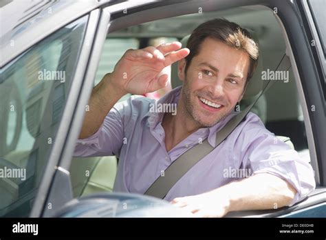 Man driving car, smiling out window and waving Stock Photo - Alamy