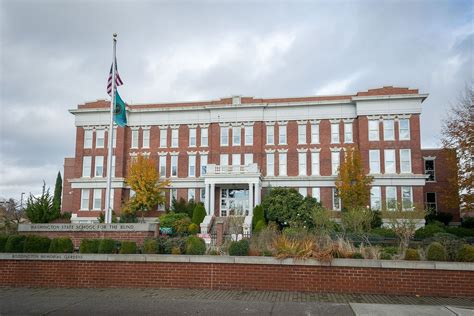 An Old Brick Building With A Flag On The Roof And Trees In Front Of It