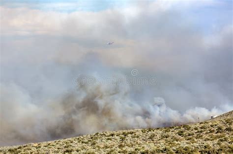 Large Orange And White Fire Tanker Flying Through Heavy Clouds Of Smoke