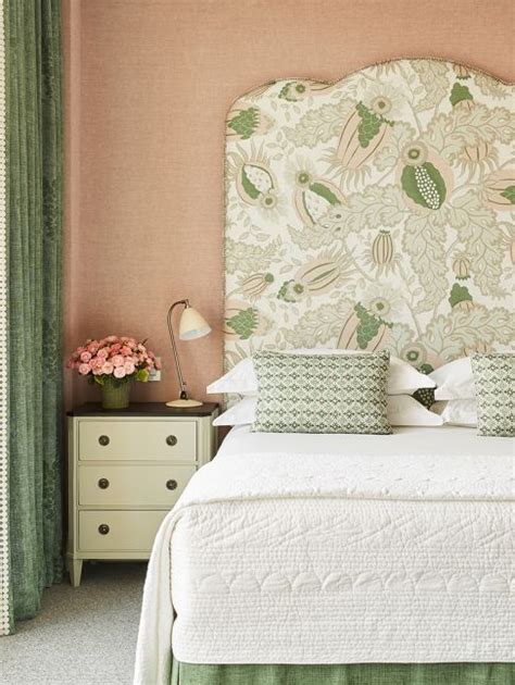 A Bedroom With Pink Walls And Green Curtains On The Window Sill Along