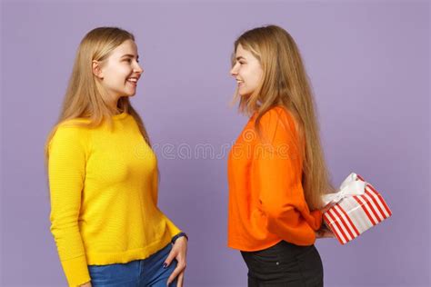 Deux Jeunes Filles Blondes De Soeurs De Jumeaux Dans La Position Colorée Vive De Vêtements