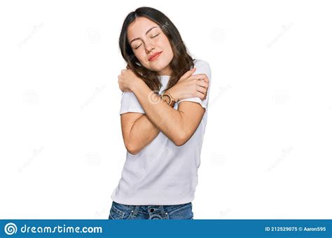 Young Beautiful Woman Wearing Casual White T Shirt Hugging Oneself