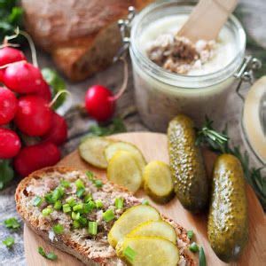 A Wooden Plate Topped With Bread And Cucumbers Next To Other Food On A