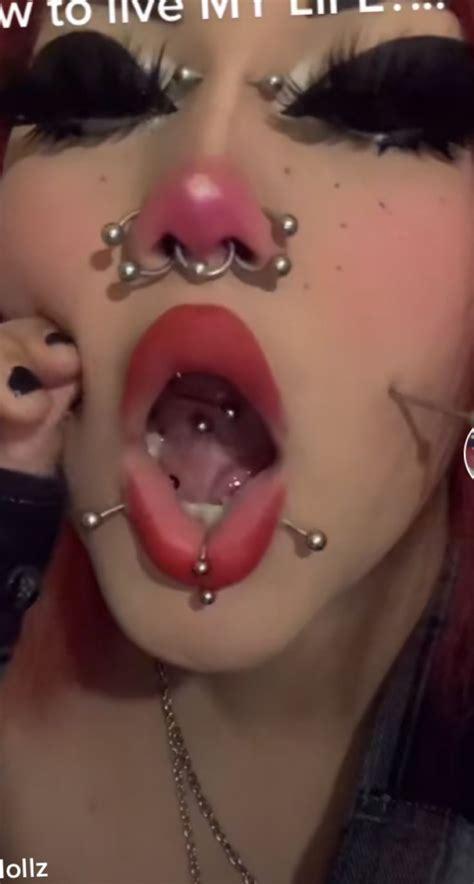 A Woman With Piercings On Her Face And Tongue