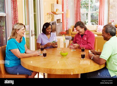 Two Mature Couples Sitting At The Table And Playing Cards Stock Photo Alamy