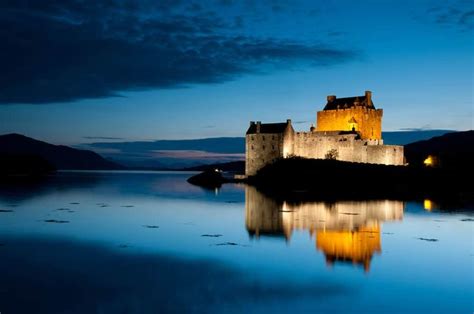 A Castle Sitting On Top Of A Lake At Night