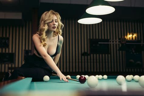 Femme blonde jouant en appréciant le billard tenir la queue frapper des boules de billard