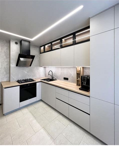 A Modern Kitchen With White Cabinets And Black Appliances On The