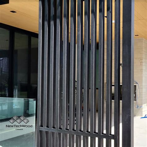 A Black Gate Is Open On The Side Of A Building That Has Glass Doors In