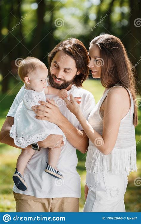 De Jonge Mooie Ouders Gekleed In Witte Kleren Houden Ergens Hun Kleine