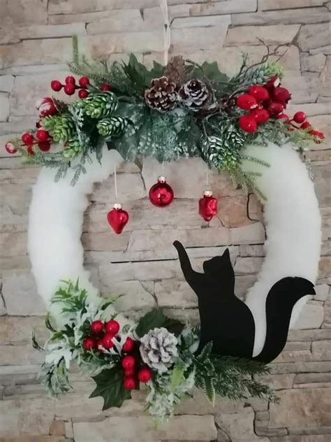 A Christmas Wreath With A Black Cat And Pine Cones Hanging From It S Side