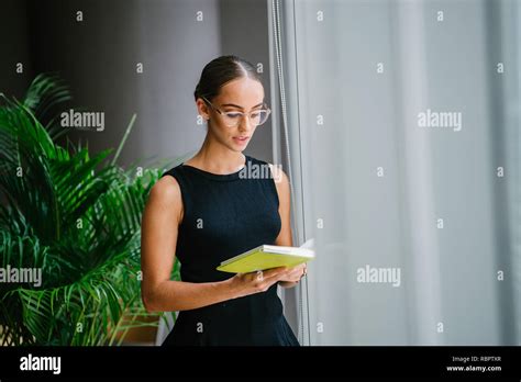 Portrait d une jeune belle et élégante femme blonde à lunettes en lisant un livre par une
