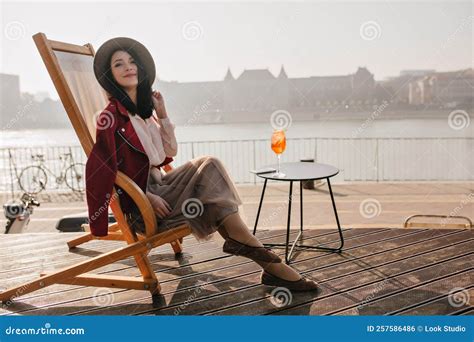 Smiling Brunette Girl Sitting On Recliner Enjoying Vacation In Europe Portrait Of Well Dressed