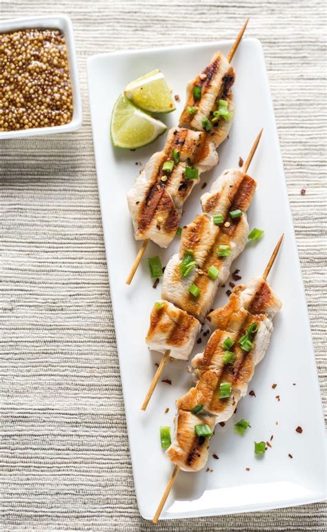 Grilled Chicken Skewers With Green Onions And Cilantro On A White Plate