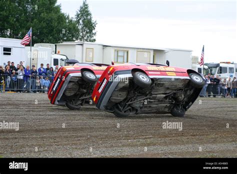 Two cars driving on two wheels in stunt car show Stock Photo - Alamy