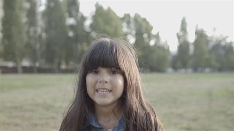 Vídeo Gratis Retrato de una linda chica latina parada en el parque sonriendo a la cámara y