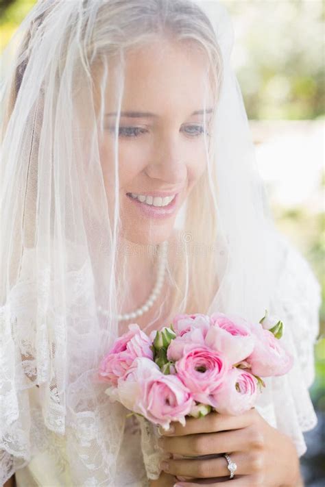 Smiling Bride Wearing Veil Over Face Holding Bouquet Stock Image