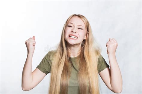 Portrait Of Overjoyed Woman Clenches Fists With Happiness Poses