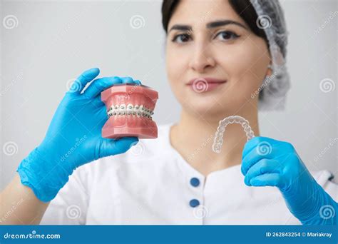 Dentist Showing Model Of Human Jaw With Wire Braces And Aligners To