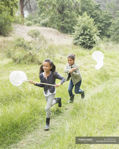 Girls using butterfly nets in field — indian ethnicity, grass - Stock