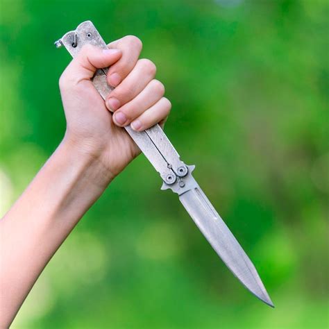 Mano Femenina Sosteniendo Un Cuchillo Sobre Fondo Verde Borroso Foto