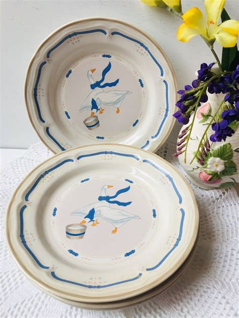 Two White Plates With Blue Designs On Them Next To A Vase Filled With