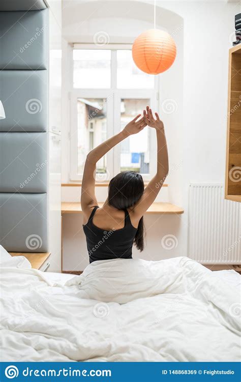 Back View Of Beautiful Young Woman In The Bedroom Waking Up And Stretch