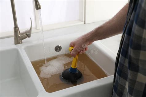 Man Using Plunger To Unclog Sink Drain in Kitchen, Closeup Stock Image ...