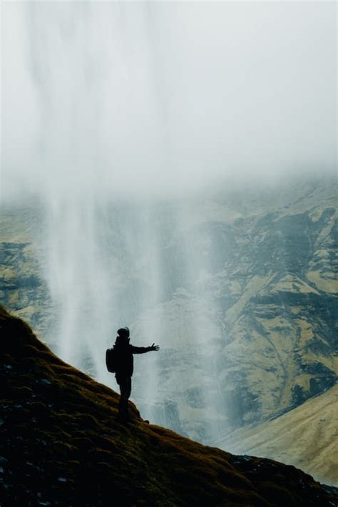 Person Standing under Flowing Water of Waterfall · Free Stock Photo