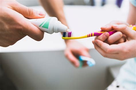 Primer Plano Las Manos Poniendo Pasta De Dientes En El Cepillo Foto Gratis